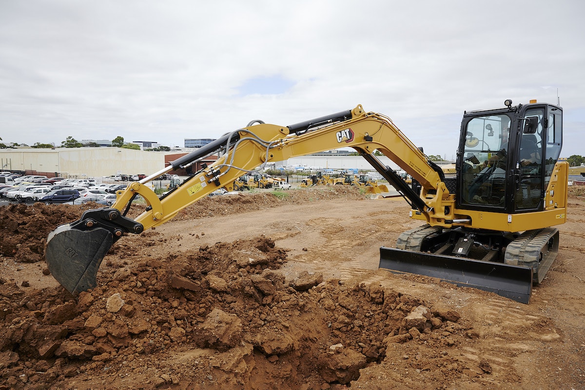 Yellow excavator with a front blade digging soil on a construction site