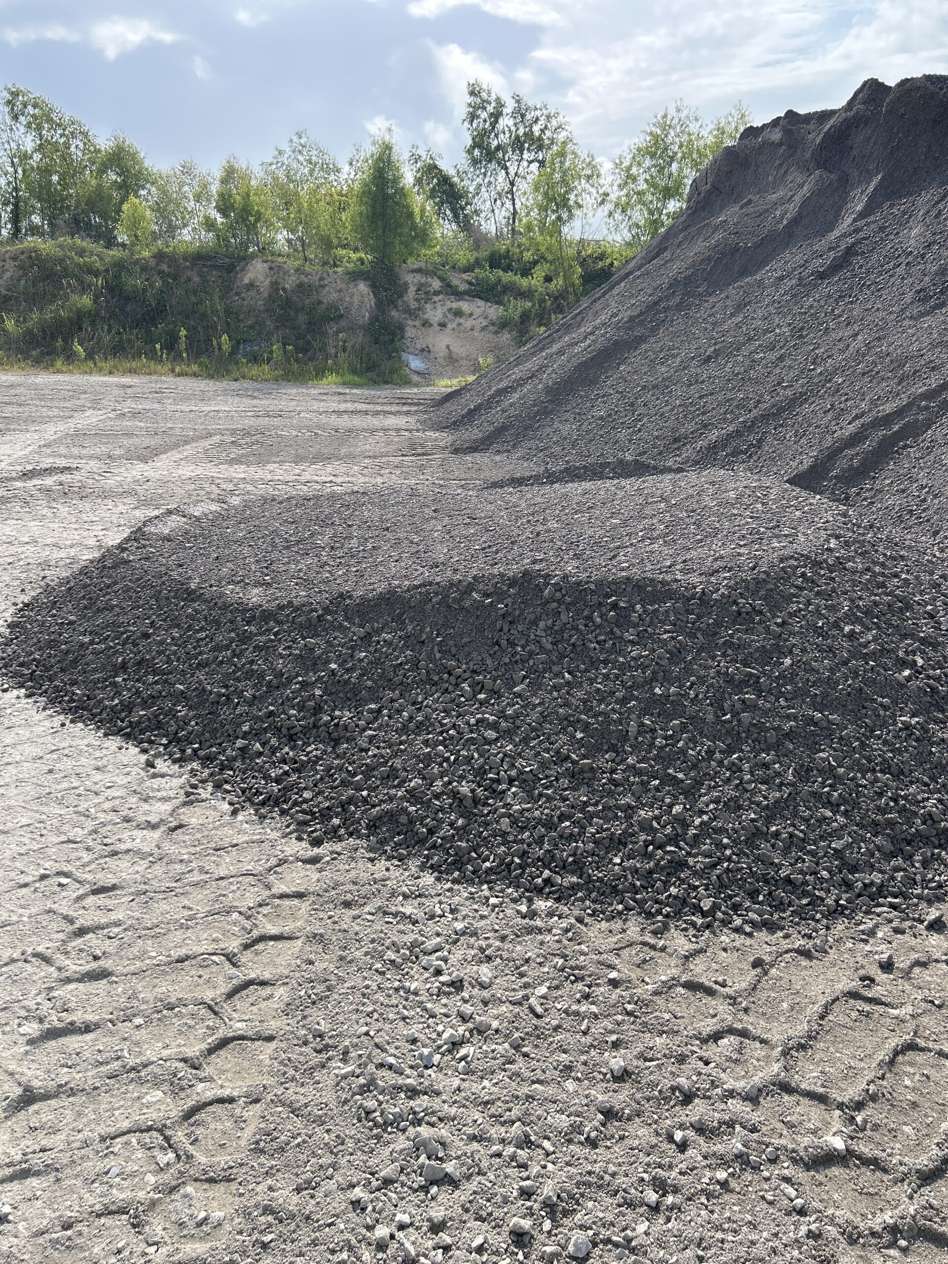 Piles of dark crushed rock on a paved yard