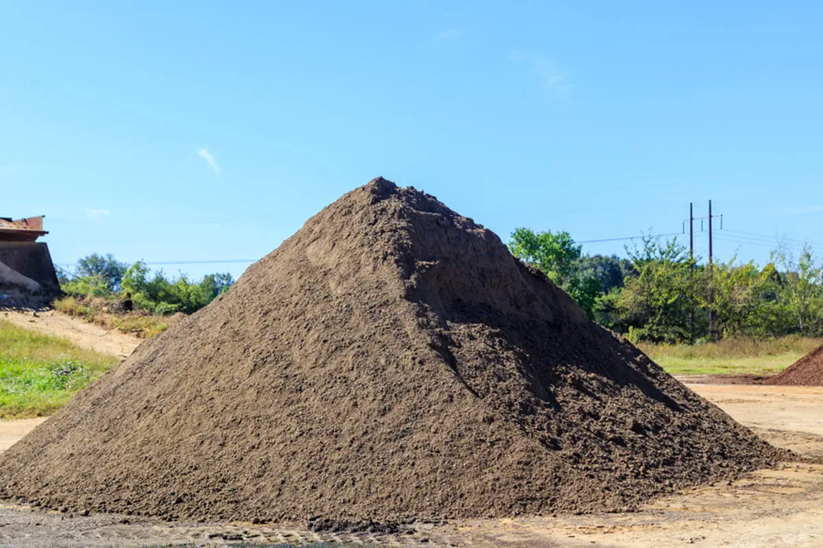 Large pile of dark topsoil on an open site